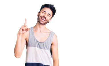 Gündelik kıyafetler giyen genç İspanyol bir numarayı gösterip işaret ederken kendinden emin ve mutlu bir şekilde gülümsüyor.. 