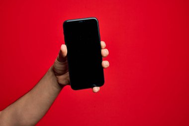 Kafkas genci elinde akıllı telefon var. İzole edilmiş kırmızı arkaplanda ekranı gösteriyor.