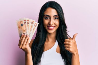 Güzel İspanyol kadın Birleşik Krallık 'ı elinde tutuyor mutlu ve pozitif gülümsüyor, başparmağıyla mükemmel ve onay işareti yapıyor. 