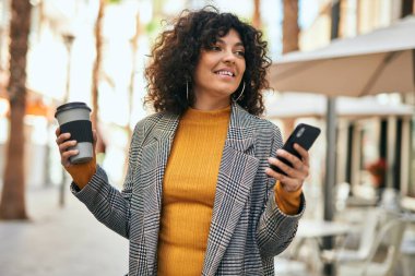Genç İspanyol iş kadını akıllı telefon kullanıyor. Şehirde kahve içiyor..