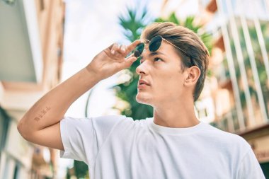 Şehirde yürüyen, ciddi bir ifadeye sahip beyaz bir genç..