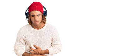 Mide bulantısı, acı verici bir hastalık yüzünden kulaklık takan genç bir İspanyol adam müzik dinliyor. Ağrı kavramı. 