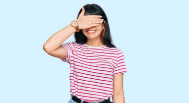 Günlük kıyafetler giyen, gülümseyen ve gülen genç İspanyol kız şaşırmak için gözlerini kapatıyor. kör kavram. 