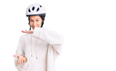 Güzel esmer, bisiklet kaskı takan, spor kıyafetler giyen, büyük ve büyük beden işareti gösteren, ölçü sembolü olan güzel bir kadın. Kameraya bakıp gülümsüyor. ölçüm kavramı. 