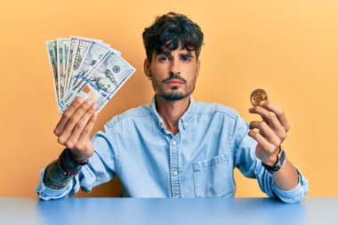 Elinde dolar ve bitcoin tutan İspanyol asıllı genç adam yüzünde ciddi bir ifadeyle rahatladı. Basit ve doğal bir şekilde kameraya bakıyorsun.. 