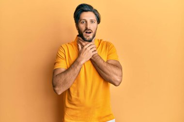 Günlük sarı tişört giyen genç İspanyol adam bağırıyor ve boğuluyor çünkü acı verici bir boğulma var. Sağlık problemi. Boğulma ve intihar konsepti. 