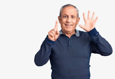 Kıdemli yakışıklı adam gündelik polo giyip altı numaralı parmaklarıyla işaret ederken kendinden emin ve mutlu bir şekilde gülümsüyor.. 