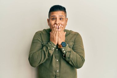 Gündelik kıyafetler giyen genç Latin adam gülüyor ve utanıyor kıkırdıyor ağızlarını ellerle kapatıyor, dedikodu ve skandal konsepti yapıyor. 