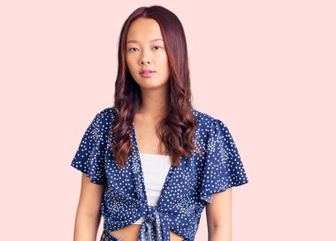 Gündelik kıyafetler giyen genç, güzel Çinli kız yüzünde ciddi bir ifadeyle rahatlamış. Basit ve doğal bir şekilde kameraya bakıyorsun.. 