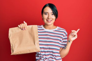 Kısa saçlı, güzel bir kadın. Paket çantasından al. Gülümse. 