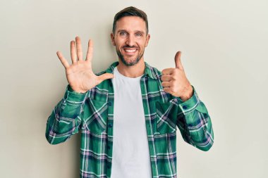 Sakallı, sıradan giyinen, altı numaralı parmaklarıyla gösteriş yapan yakışıklı, kendinden emin ve mutlu bir adam.. 