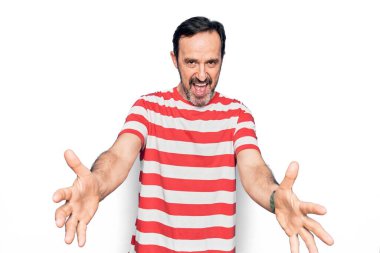 Orta yaşlı, çizgili tişört giyen yakışıklı adam izole edilmiş beyaz arka planda dikilip kameraya sarılmak için gülümseyerek bakıyor. Mutluluğu kucaklayan neşeli bir ifade..