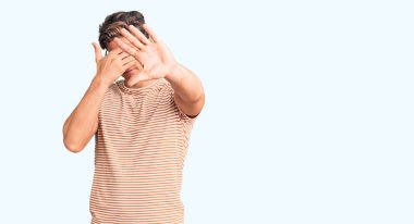 Gündelik kıyafetler giyen, gözlük takan, ellerle gözleri kapayan ve üzgün ve korku ifadeleriyle jest yapan genç yakışıklı bir adam. utangaç ve olumsuz kavram. 