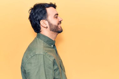 Latin kökenli genç adam rahat bir görünüm takınıyor, rahat bir görünüm takınıyor, kendine güvenen bir gülümsemeyle.. 