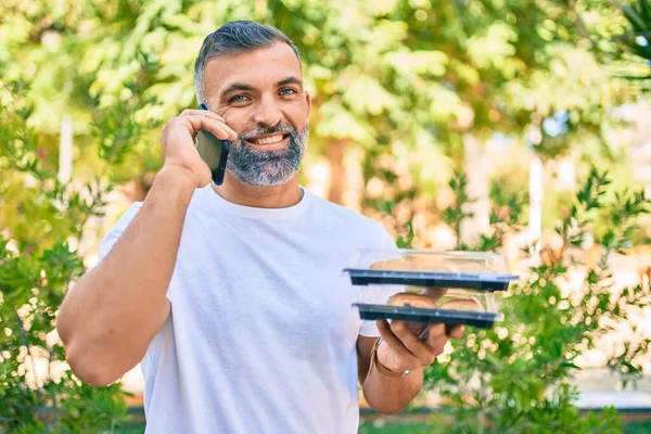 Hombre Pelo Gris Mediana Edad Hablando Teléfono Inteligente Sosteniendo Comida —  Fotos de Stock
