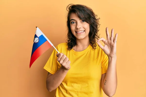 Молодая Латиноамериканка Флагом Словении Делает Знак Пальцами Улыбаясь Дружелюбный Жест — стоковое фото
