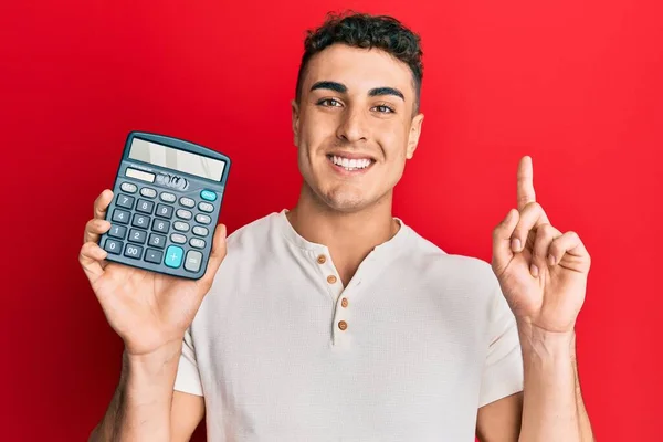 Hispanic Young Man Showing Calculator Device Surprised Idea Question Pointing — Stock Photo, Image