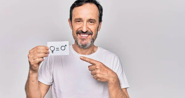 Middle age man asking for rights holding paper with equality male and female concept smiling happy pointing with hand and finger