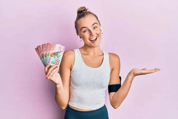 Beautiful Blonde Sport Woman Holding 100 New Zealand Dollars Banknote — Stock Photo, Image