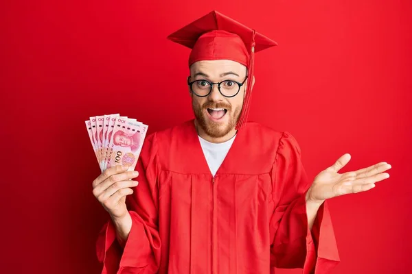 Ung Rödhårig Man Bär Examen Mantel Hålla 100 Yuan Firar — Stockfoto