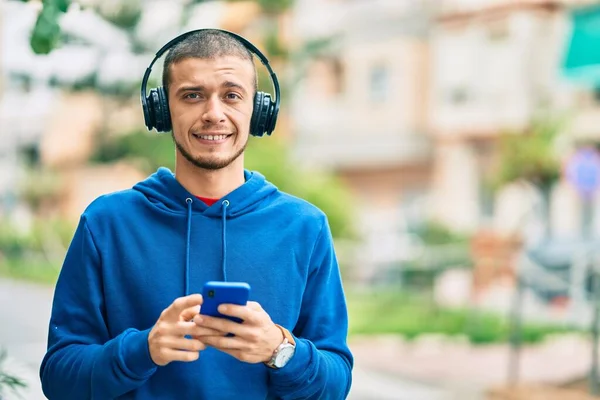 Jonge Spaanse Man Glimlacht Gelukkig Met Behulp Van Smartphone Koptelefoon — Stockfoto