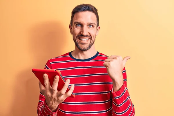 Joven Hombre Guapo Sosteniendo Touchpad Pie Sobre Fondo Amarillo Aislado —  Fotos de Stock