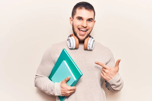 Jovem Homem Bonito Segurando Livro Usando Fones Ouvido Sorrindo Feliz — Fotografia de Stock