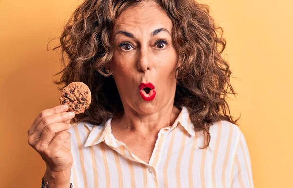 Mulher Meia Idade Morena Segurando Biscoito Chocolate Sobre Fundo Amarelo — Fotografia de Stock