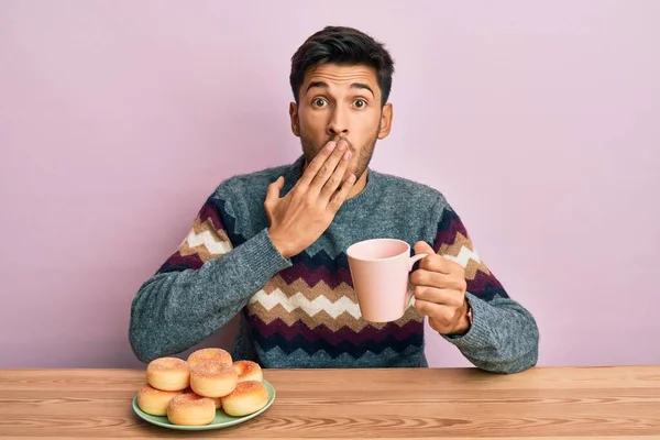 Young Handsome Man Eating Doughnuts Drinking Coffee Covering Mouth Hand — Stock Photo, Image