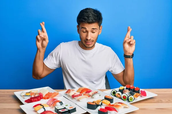 Joven Hombre Guapo Comiendo Sushi Sentado Mesa Gesto Cruzado Sonriendo — Foto de Stock