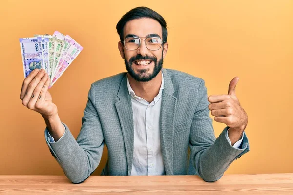 Young Hispanic Man Holding Indian Rupee Banknotes Sitting Table Smiling — Stock Photo, Image