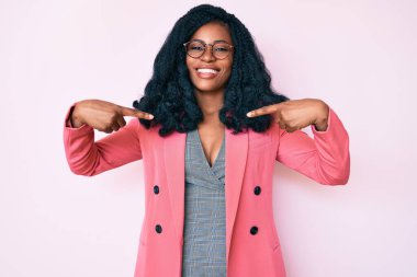 İş ceketi ve gözlük takan güzel Afrikalı bir kadın. Kendine güvenen, gülümseyen, kendini gururlu ve mutlu bir şekilde gösteren bir kadın.. 