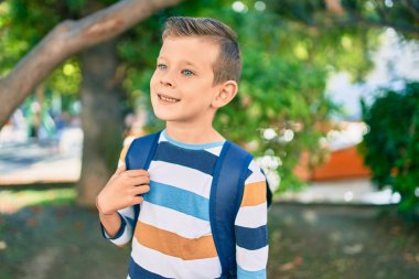 Kafkasyalı bir öğrenci parkta mutlu bir şekilde gülümsüyor..