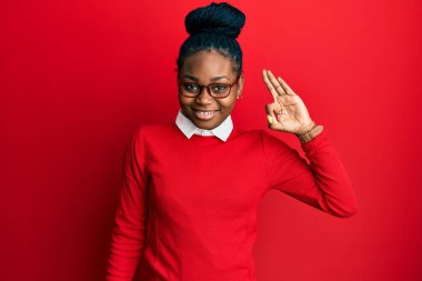 Sıradan kıyafetler ve gözlüklerle gülümseyen genç Afro-Amerikalı kadın el ve parmaklarıyla 