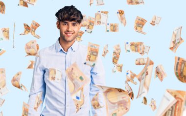 Yüzünde mutlu ve havalı bir gülümseme olan gündelik tişört giyen genç bir İspanyol. şanslı kişi.