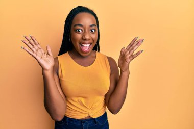 Genç Afro-Amerikalı kadın gündelik giysiler giyip çılgınlığı kutluyor ve başarıya hayret ediyor. Kolları açık, gözleri açık heyecanla haykırıyor. Kazanan konsept 