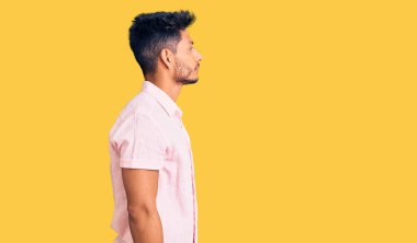 Yakışıklı Latin Amerikalı sıradan bir yaz tişörtü giyen rahat profil pozu veren, doğal yüzlü ve kendinden emin gülümseyen genç adam.. 