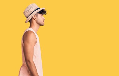 Yazlık şapka takan genç İspanyol adam, rahat bir görünüm ve kendine güvenen bir gülümseme takınıyor.. 