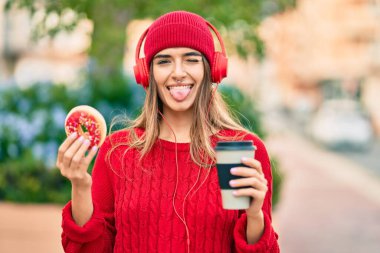 Genç İspanyol kadın şehirde kulaklık takarak kahvaltı yapıyor..