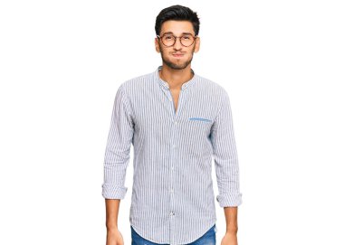 Gündelik kıyafetler giyen ve gözlüklü, komik yüzlü, yanakları şişen genç yakışıklı bir adam. Havayla şişmiş ağız, çılgın bir ifade.. 