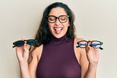 Ortadoğulu güzel bir kadın farklı gözlükler tutuyor. Dilini çıkartıyor. Komik bir ifadeyle mutlu.. 