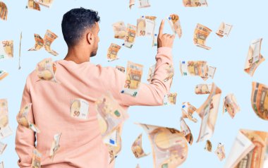 Latin asıllı genç adam gündelik giysiler giyip geriye doğru poz veriyor.