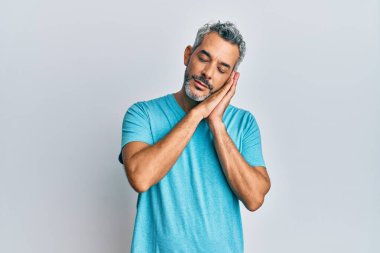 Orta yaşlı, gri saçlı, günlük giysiler giyen, yorgun uyuyan, hayal kuran, elleriyle poz veren ve gözleri kapalı gülümseyen bir adam.. 