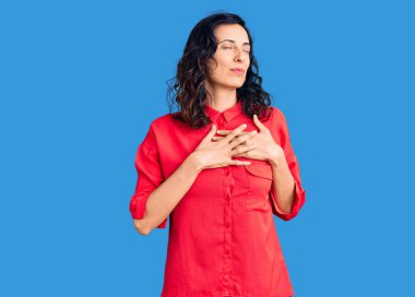 Gündelik kıyafetler giyen, göğsünde elleri kapalı, yüzünde minnet dolu bir jest olan genç ve güzel bir İspanyol kadın. sağlık kavramı. 