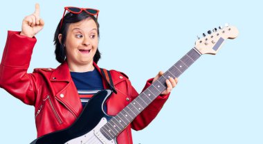 Down sendromlu esmer kadın elektro gitar çalıyor. Bir fikir ya da soru işareti ile şaşırmış, mutlu yüzlü, bir numara. 