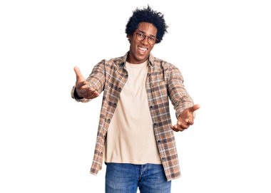 Afro saçlı ve gözlüklü yakışıklı Afro-Amerikalı adam. Neşeli gülümsüyor, kollarını açıyor. Hoş geldin, olumlu ve kendinden emin selamlar. 