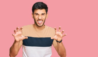 Genç, yakışıklı, günlük kıyafetler giymiş komik gülüyor. Pençe hareketlerini kedi gibi yapıyor. Agresif ve seksi bir ifade. 