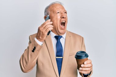 Kafkasyalı kıdemli bir adam akıllı telefondan konuşuyor ve bir fincan kahve içiyor kızgın ve öfkeli bir şekilde bağırıyor, öfkeyle bağırıyor. öfke ve agresif konsept. 