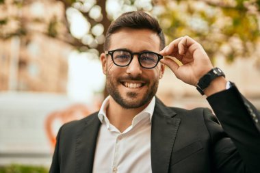 Genç İspanyol işadamı gülümseyerek şehirde mutlu mesut duruyor..