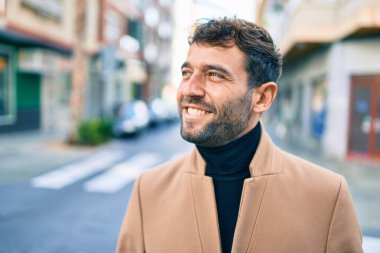 Zarif ceket giyen yakışıklı iş adamı dışarıda mutlu bir şekilde gülümsüyor.